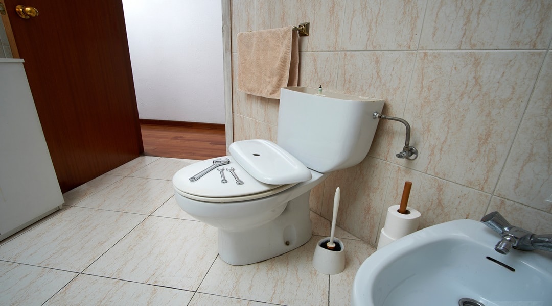 Plumber's tools near toilet bowl in bathroom